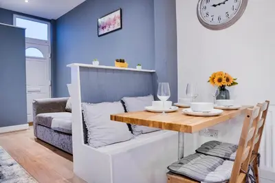 a dining room with a table and a clock on the wall at Birkenhead - 2 bedroom house in Birkenhead