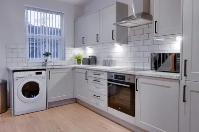 a white kitchen with a washer and dryer in it at Birkenhead - 2 bedroom house in Birkenhead