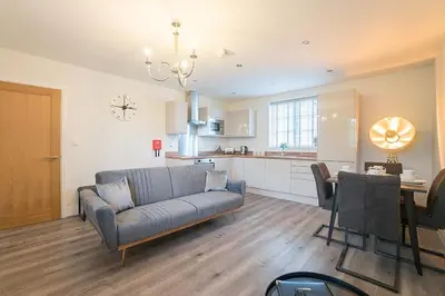 a living room with a couch and a kitchen at The Queens Arms Apartments in Liverpool