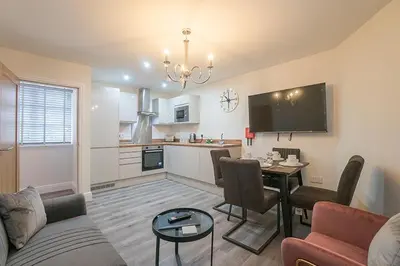 a living room with a couch and a table and a kitchen at The Queens Arms Apartments in Liverpool