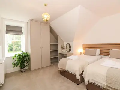 a attic bedroom with two beds and a window at The Arthur Suite Stone Cross Mansion in Ulverston