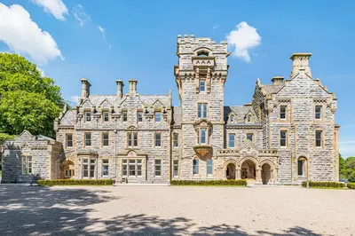 a large stone building with a clock tower on it at The Arthur Suite Stone Cross Mansion in Ulverston