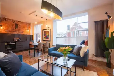a living room with a blue couch and a table at Capri Stays - Apartment One in Blackpool
