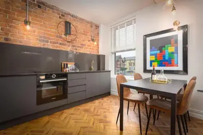 a kitchen with a dining table and a brick wall at Capri Stays - Apartment One in Blackpool