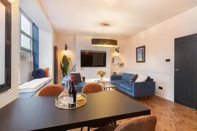 a living room with a blue couch and a table at Capri Stays - Apartment One in Blackpool
