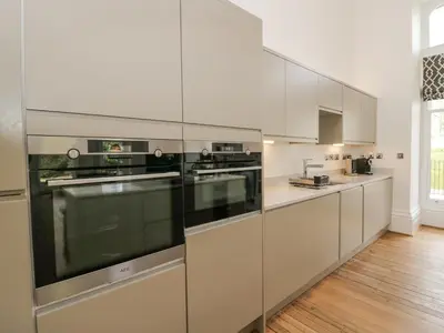 a kitchen with white cabinets and stainless steel appliances at The Myles Suite Stone Cross Mansion in Ulverston