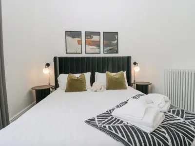 a bedroom with a large white bed with two lamps at The Myles Suite Stone Cross Mansion in Ulverston