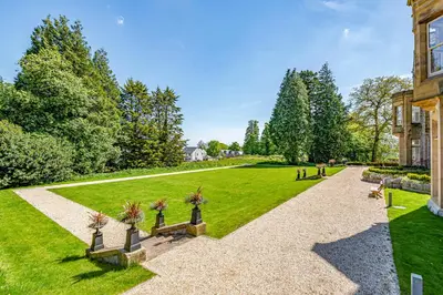 a garden with benches in front of a building at The Myles Suite Stone Cross Mansion in Ulverston