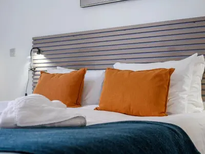 a bed with orange and white pillows on it at The Theobold Suite Stone Cross Mansion in Ulverston