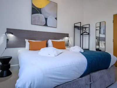 a bedroom with a large white bed with orange pillows at The Theobold Suite Stone Cross Mansion in Ulverston