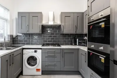a kitchen with gray cabinets and a washer and dryer at The Anfield Inn in Liverpool