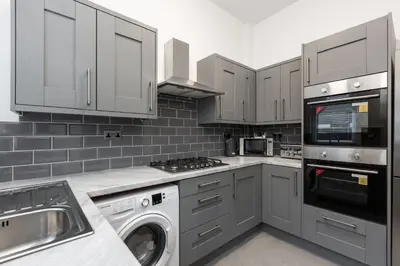 a kitchen with white cabinets and a washer and dryer at The Anfield Inn in Liverpool