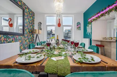 a dining room with a wooden table with green chairs at Empress Hall Blackpool by Charles Alexander Short Stay - Sleeps 20 in Blackpool