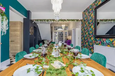 a dining room with a long table and green chairs at Empress Hall Blackpool by Charles Alexander Short Stay - Sleeps 20 in Blackpool