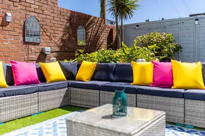a blue couch with colorful pillows on a patio at Empress Hall Blackpool by Charles Alexander Short Stay - Sleeps 20 in Blackpool