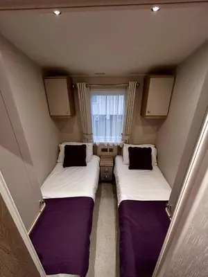 two beds in a small room with a window at Lake District Willerby Vogue Lodge, Lake View on Haven Lakeland Gold Grade in Flookburgh
