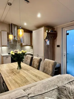 a kitchen with a wooden table with a vase of flowers at Lake District Willerby Vogue Lodge, Lake View on Haven Lakeland Gold Grade in Flookburgh