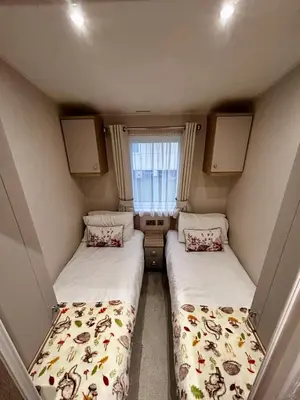 two beds in a small room with a window at Lake District Willerby Vogue Lodge, Lake View on Haven Lakeland Gold Grade in Flookburgh