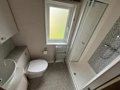 a small bathroom with a toilet and a shower at Lake District Willerby Vogue Lodge, Lake View on Haven Lakeland Gold Grade in Flookburgh