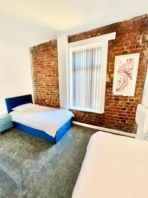 a bedroom with two beds and a brick wall at Winter Gardens Presidential Suite Blackpool in Blackpool