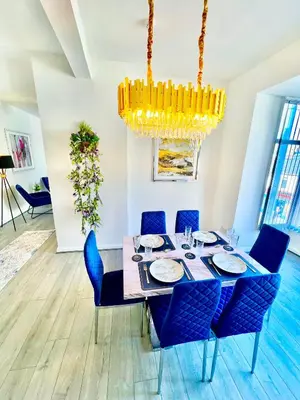 a dining room with a table with blue chairs and a chandelier at Winter Gardens Presidential Suite Blackpool in Blackpool