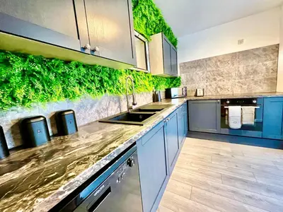 a kitchen with blue cabinets and a green wall at Winter Gardens Owners Suite Blackpool in Blackpool