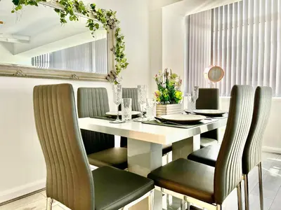 a dining room with a white table with green chairs at Winter Gardens Owners Suite Blackpool in Blackpool