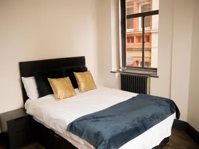 a bedroom with a bed with yellow pillows and a window at New Oxford House Apartments By Happy Days in Liverpool
