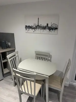 a dining room table and chairs with a white table at The Welcome Apartment in Blackpool