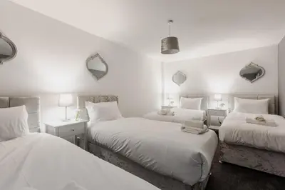 a bedroom with two beds with white sheets and mirrors at RST Cumberland Street in Liverpool