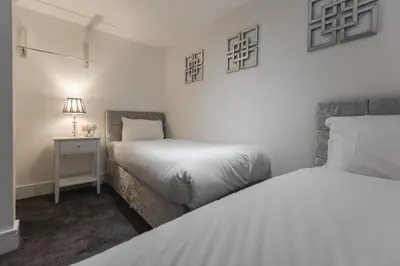 a bedroom with two beds and a table with a lamp at RST Cumberland Street in Liverpool