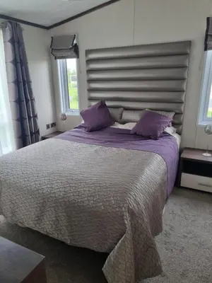 a bedroom with a large bed with purple pillows at Pemberton Arrondale Lodge, Lakeside View (Haven Lakeland) in Flookburgh