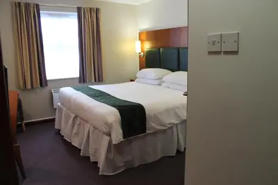 a hotel room with a bed and a window at The Villa Express in Kirkham