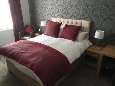 a bedroom with a large bed with red pillows at The Villa Express in Kirkham