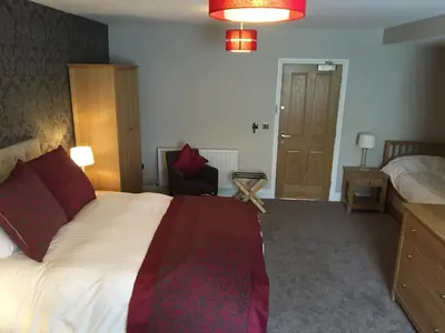 a hotel room with a large bed and a chair at The Villa Express in Kirkham