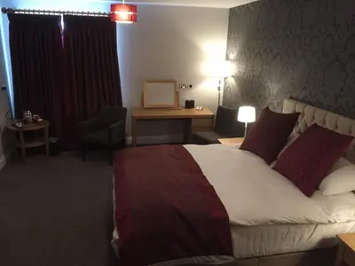 a hotel room with a large bed and a desk at The Villa Express in Kirkham