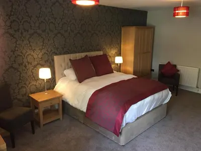 a bedroom with a large bed and two chairs at The Villa Express in Kirkham