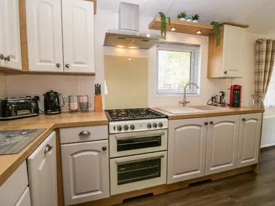 a kitchen with white cabinets and a stove top oven at Lakeland Dream South Lakeland Leisure Lodge in Carnforth