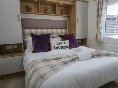 a bedroom with a large bed with purple pillows at Lakeland Dream South Lakeland Leisure Lodge in Carnforth