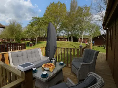 a patio with a couch and chairs on a deck at Lakeland Dream South Lakeland Leisure Lodge in Carnforth