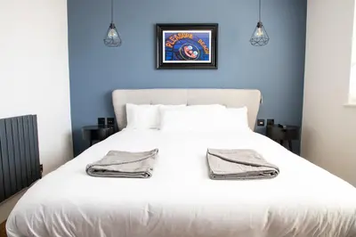 a bedroom with a white bed with a blue wall at Withnell Stays - Apartment Six in Blackpool