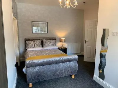 a bedroom with a bed and a chandelier at Heather Glen. Six bedroom home near the sea. in Blackpool