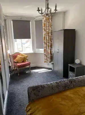a bedroom with a bed and a chair and a window at Heather Glen. Six bedroom home near the sea. in Blackpool