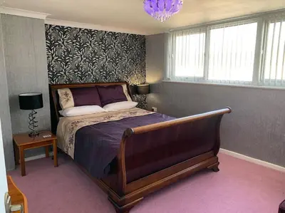 a bedroom with a bed and a chandelier at Heather Glen. Six bedroom home near the sea. in Blackpool