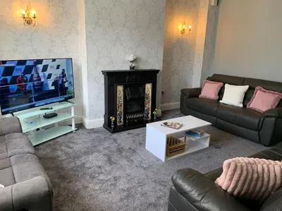 a living room with a fireplace and a television at Heather Glen. Six bedroom home near the sea. in Blackpool