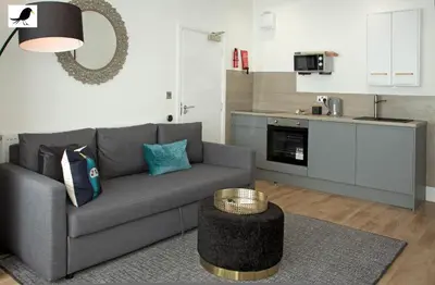 a living room with a gray couch and a kitchen at Blackbird Accommodation and Luxury Apartments room 11 in Blackpool
