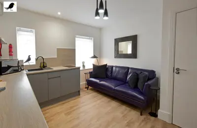 a living room with a purple couch and a kitchen at Blackbird Accommodation and Luxury Apartments room 14 in Blackpool