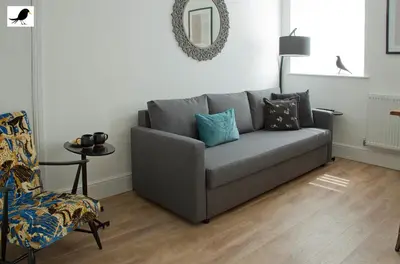 a living room with a gray couch and a chair at Blackbird Accommodation and Luxury Apartments room 15 in Blackpool