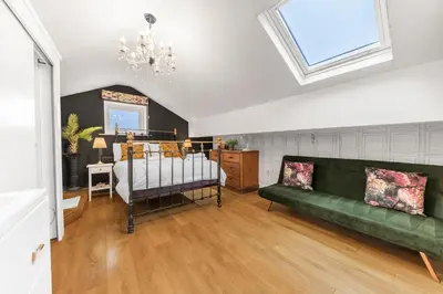 a living room with a green couch and a bed at No.1 The Coach House in Silverdale