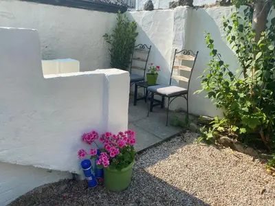 a small patio with two chairs and flowers on it at No.1 The Coach House in Silverdale